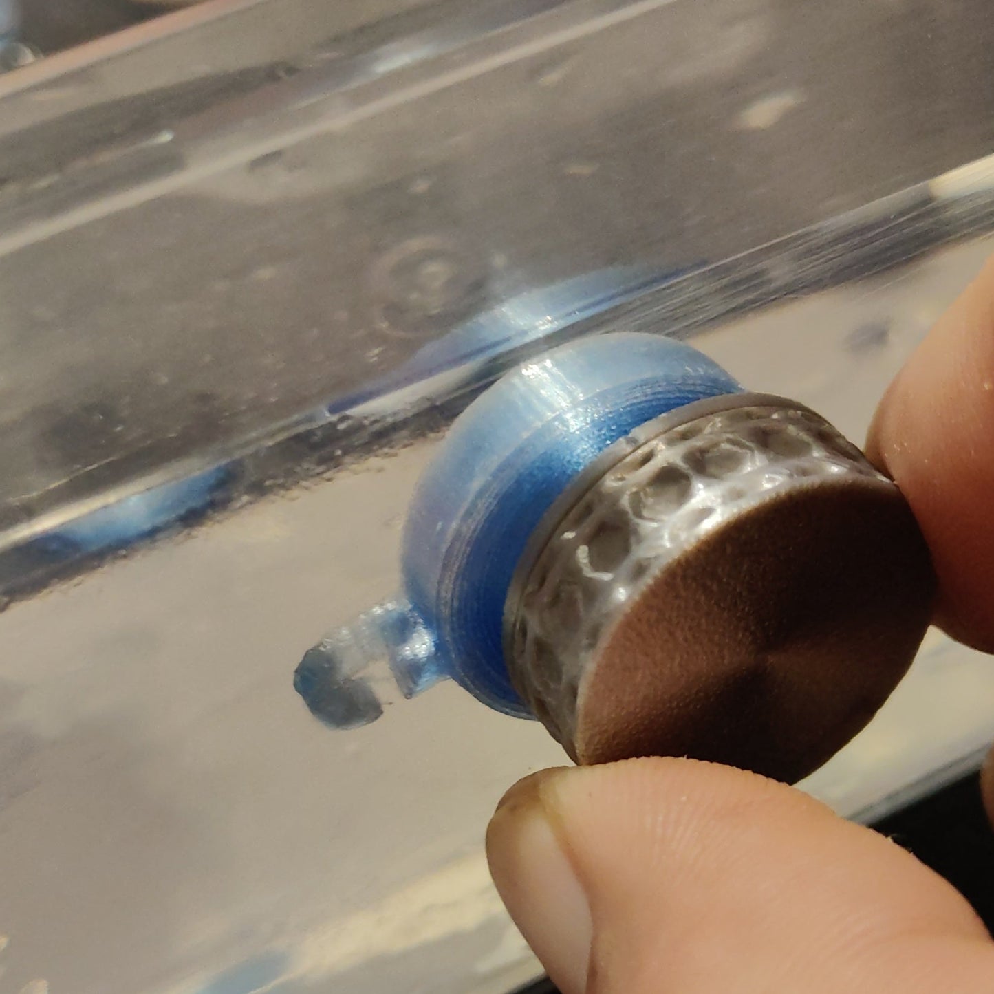 Hand using a to tighten a blue and silver on a surface.