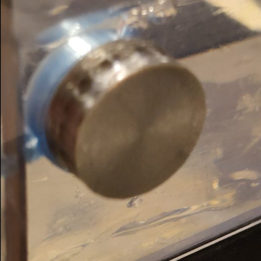 Close-up of a metallic cylindrical object on a reflective surface