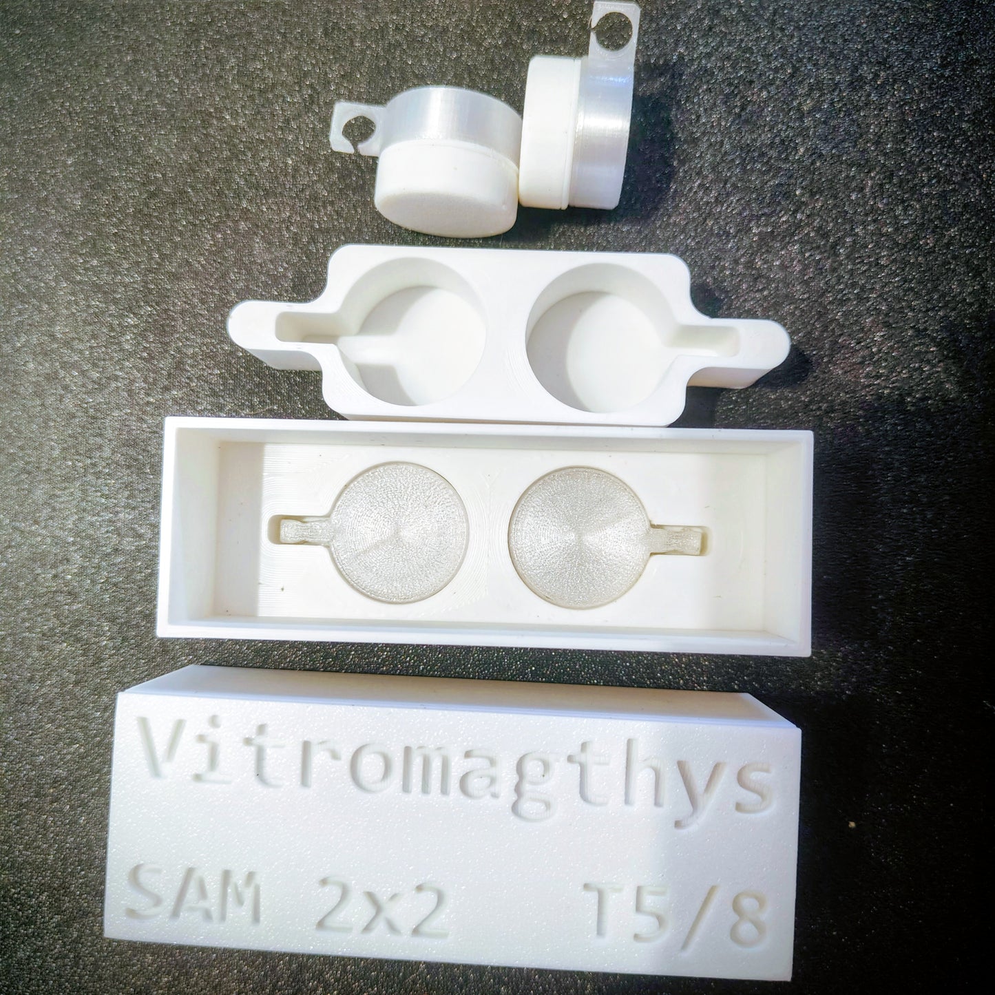 White plastic mold with spherical components on a dark surface