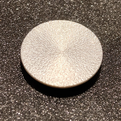 Round metallic object on a textured black surface