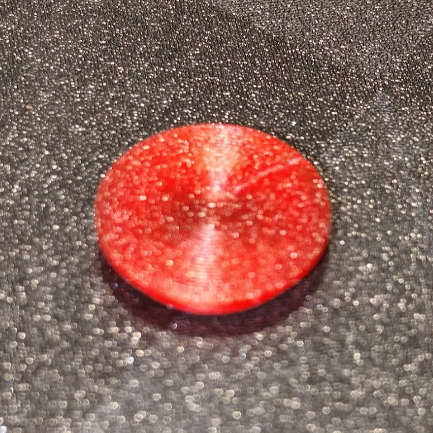 Red circular object on a textured gray surface