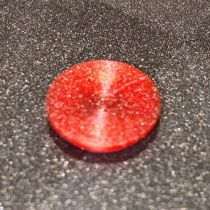 Red circular object on a textured gray surface